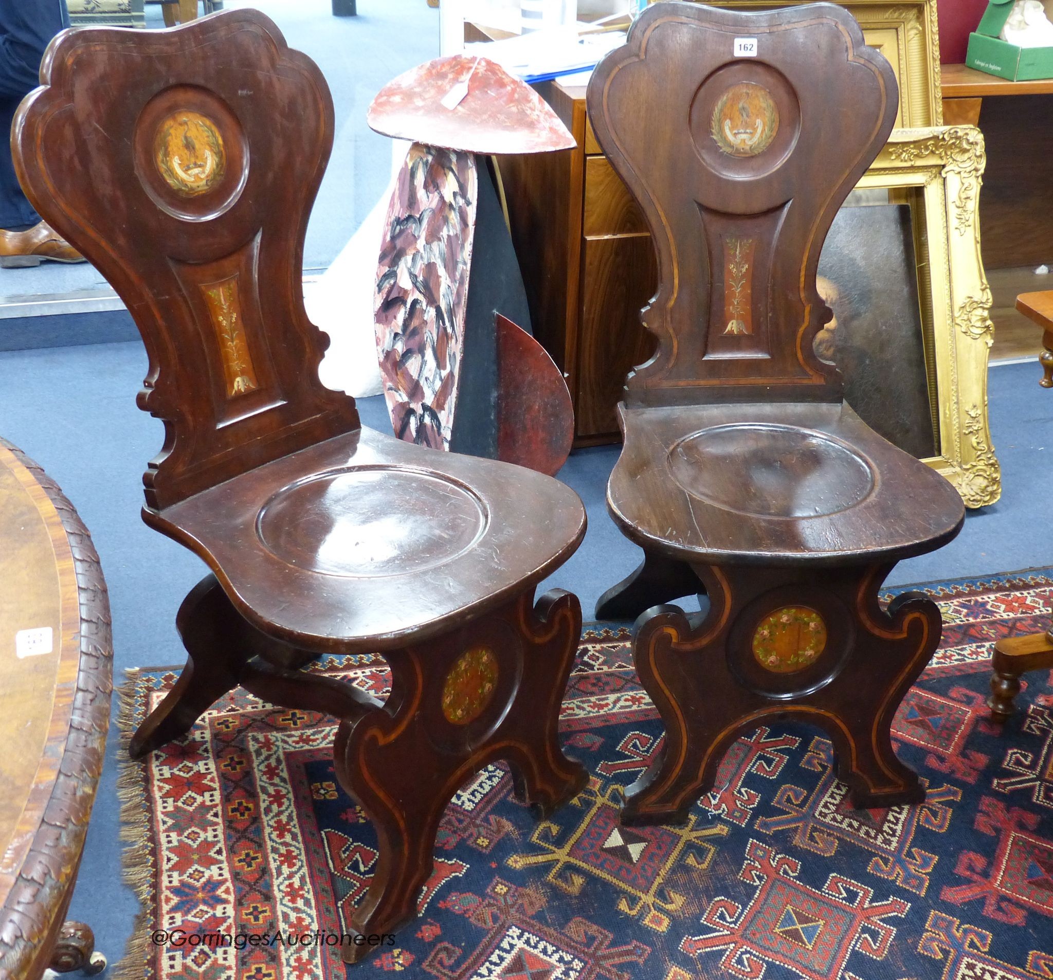 A pair of 19th century Italian style walnut hall chairs with painted armorials, width 46cm, height 99cm